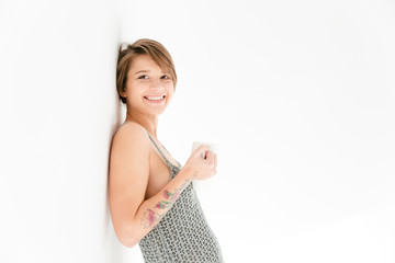 Fototapeta premium Happy cheerful young woman leaning the wall and drinking tea
