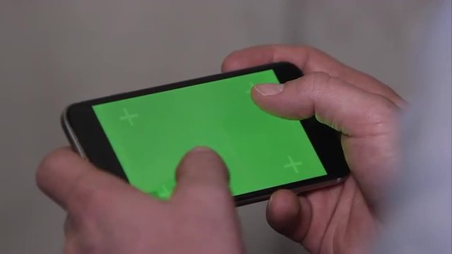 Up close shot of someone using smartphone with green screen.