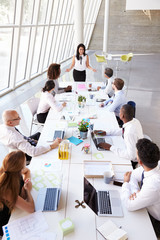 Hispanic Businesswoman Leading Meeting At Boardroom Table