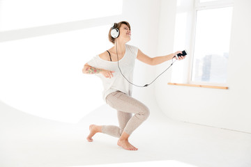 Fototapeta premium Inspired woman listening to music and imitating playing the guitar