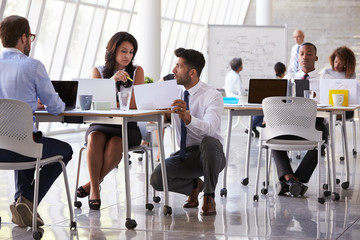 Manager Helping Staff In Busy Office Environment