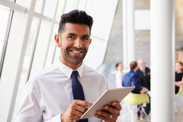 Fototapeta premium Hispanic Businessman Using Digital Tablet In Modern Office