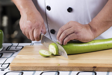 Chef slicing green eggplant