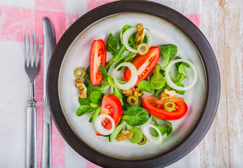 Fresh salad with lamb's lettuce, tomatoes, olives, onion and walnuts