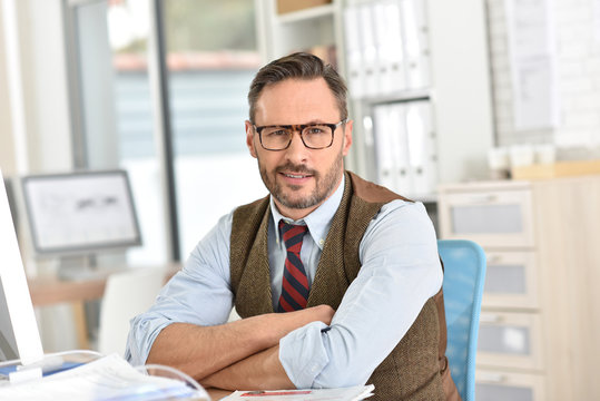 Businessman with eyeglasses sitting in front of desktop