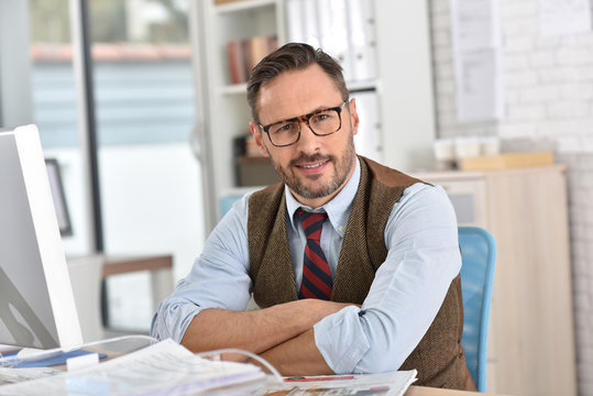 Businessman with eyeglasses sitting in front of desktop