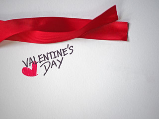 Valentine text on white paper and red ribbon