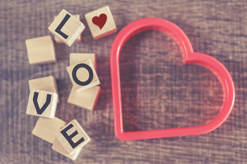 Love concept. Valentines day background with red heart and Love message written in wooden blocks