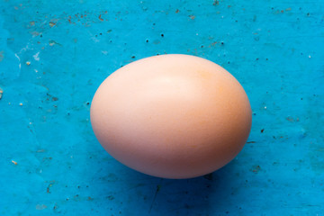 Pink chicken egg in the shell on an old blue background. Top view closeup. Shallow depth of field