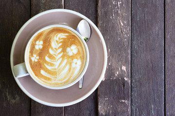 A cup of latte on wooden background.