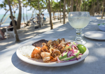 Grilled Shrimp Platter on Beach:  A fresh platter of shrimp, grilled with garlic and butter with rice, beans, and avocado - on a beach covered with Palm Trees on Soliman Bay near Tulum, Mexico