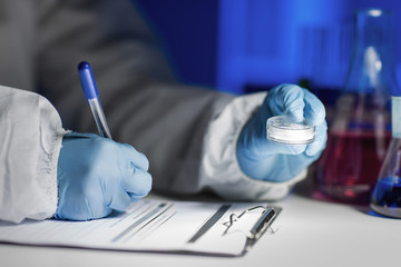 close up of scientist writing test results in lab