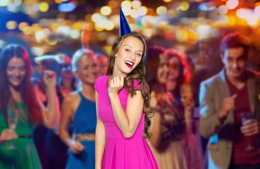 happy woman or teen in party cap at night club