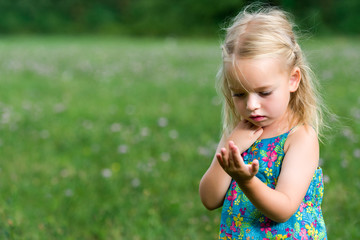Adorable young girl holding grasshopper, curiosity and education concept