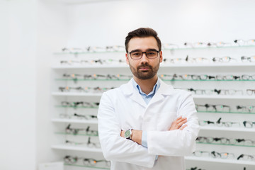man optician in glasses and coat at optics store - obrazy, fototapety, plakaty