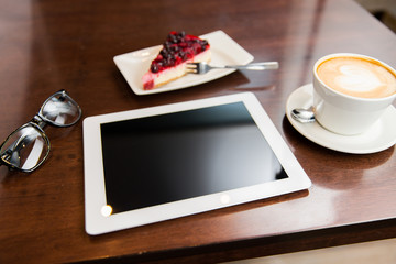 close up of tablet pc, coffee cup and cake