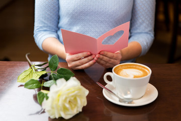 close up of woman reading greeting card and coffee