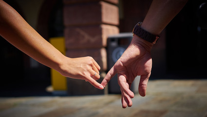 Engaged couple walking in city and holding hands / Boy and girl holding hands with engagement ring