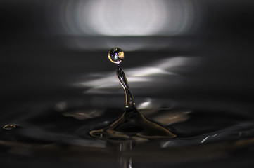 Water drop creating waves and ripples in on a dark grey background.