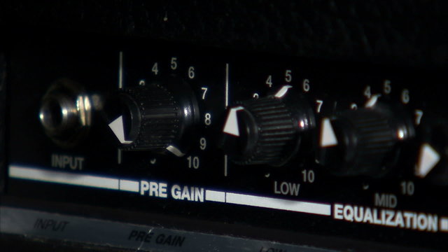 Close up of hands turning guitar amp knobs.