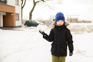 6 years old boy plays with snow in the backyard.