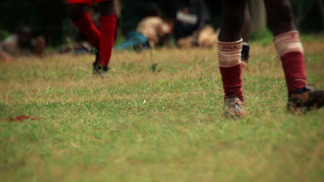 Children walking around and wearing football cleats, socks, and shin guards