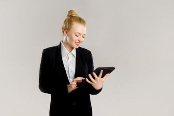 Beautiful Business girl with a tablet. black suit. smiles. Grey