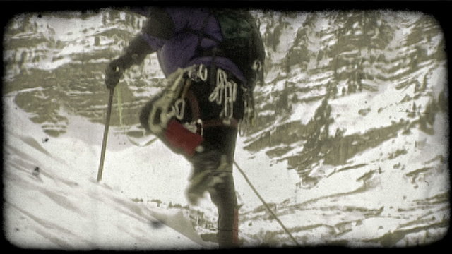 Mountain climber ascends mountain. Vintage stylized video clip.
