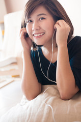 Naklejka premium Woman listening music with earphones at home.