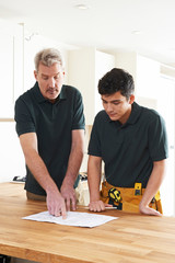 Carpenter And Apprentice Installing Luxury Fitted Kitchen