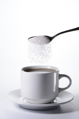 Azúcar cayendo de una cuchara en una taza de café