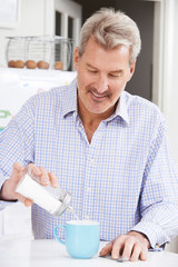 Mature Man Adding Sugar To Cup Of Coffee