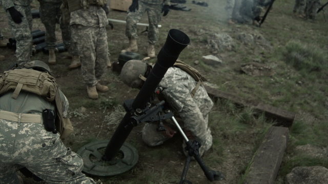 Slow motion clip of soldiers firing a mortar and others observeing.