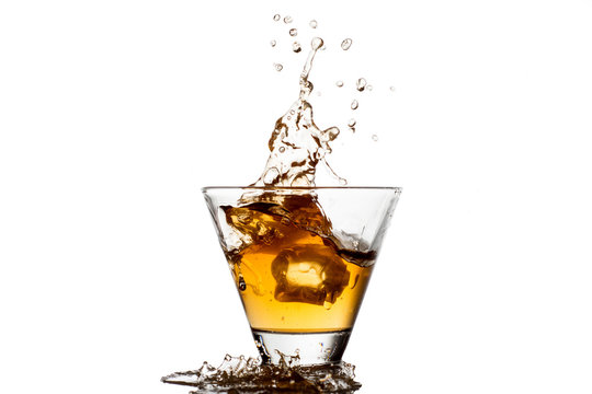Glass of whiskey with splash, isolated on white background