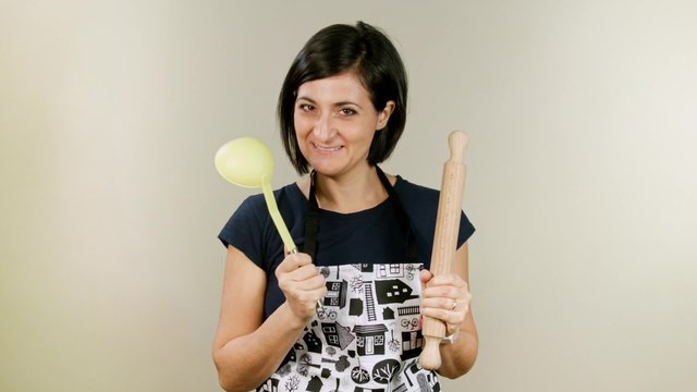 Happy young cook with rolling pin and apron, isolated in studio