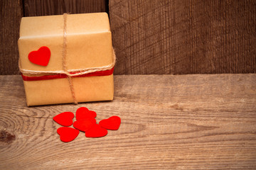 Fototapeta premium Valentines day background with gift box and red hearts on wooden