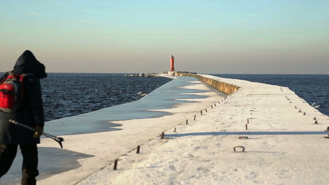 The tourist goes to the lighthouse in winter time