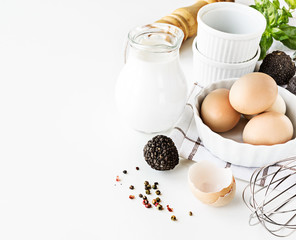 Ingredients for omelette with black trufflies on white table.