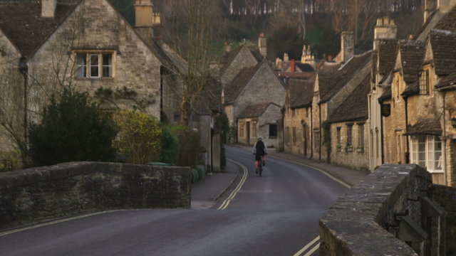 Biker passing through an old stone village in England.