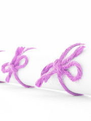 Handmade pink rope bows tied on white letter scroll isolated