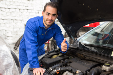 Young attractive mechanic working on a car at the garage