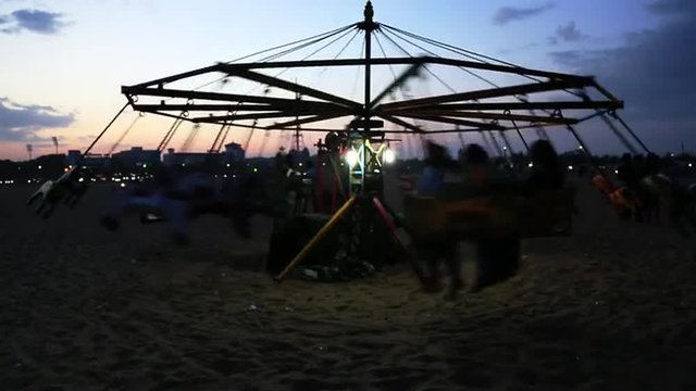 Locked-on shot of tourists enjoying in merry-go-round, Marina Beach, Mylapore, Chennai, Tamil Nadu, India