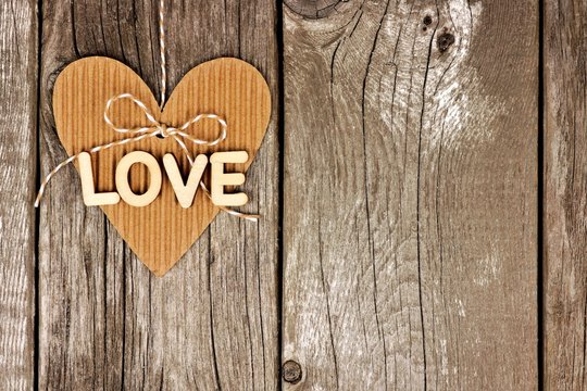 Rustic heart shaped gift tag with LOVE wood letters hanging against a vintage wooden background