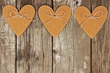Rustic heart shaped cardboard gift tags hanging against a vintage wood background