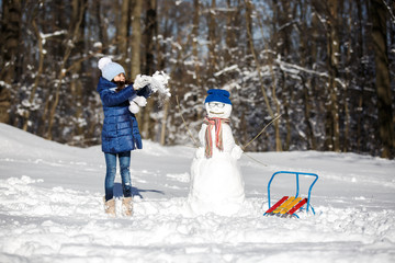 Fototapeta na wymiar Little girl playing with a snowman