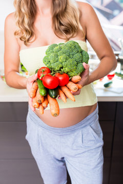 Frau ist schanger und isst gesundes Gem&uuml;se und Rohkost, Brokkoli, Tomaten und M&ouml;hren