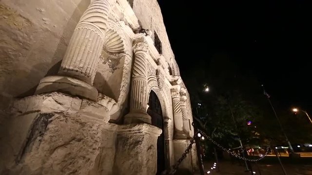 Upward panning view from the side of the Alamo at night.