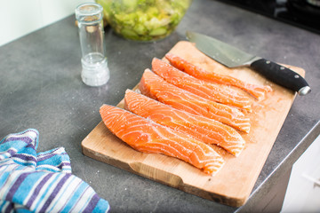 Young woman seasoning a salmon filet in her modern kitchen