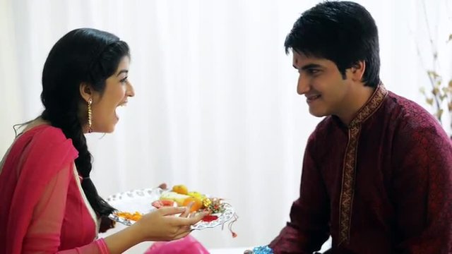 Pan shot of a teenage girl applying tilak to her brother at Raksha Bhandan