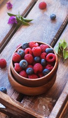 Blueberries and raspberries in bowl, on a wooden background, selective focus
